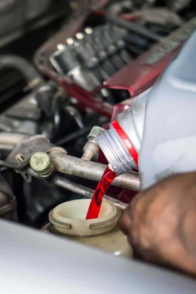 Car mechanic pouring transmission fluid to the car engine