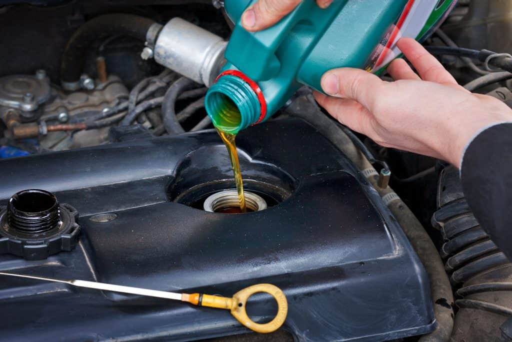 Car mechanic refilling the oil with new engine oil