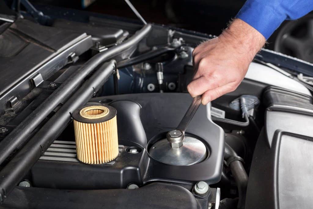 Car mechanic replacing the car engine oil filter with a new one