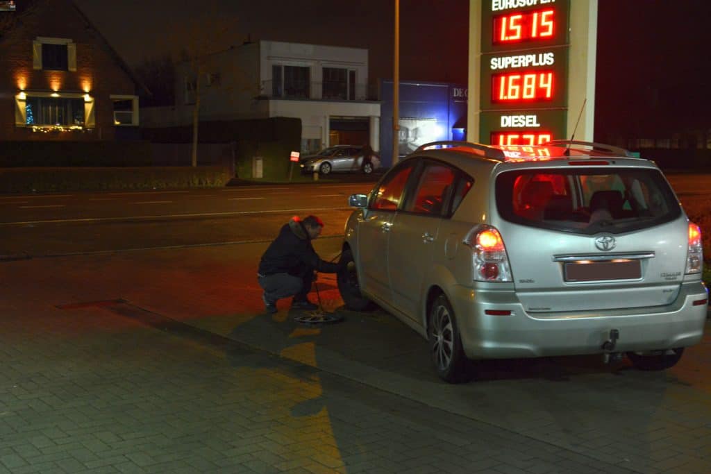 Driver checking the tire pressure of his car