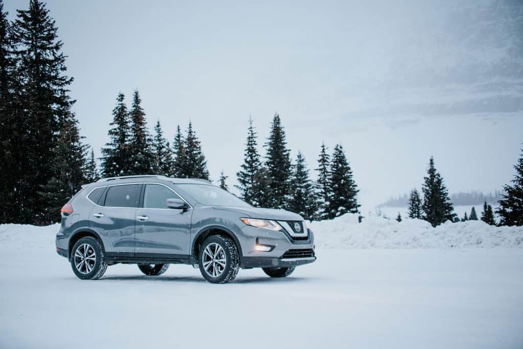 Grey Nissan Rogue parked amidst snowy winter scene.