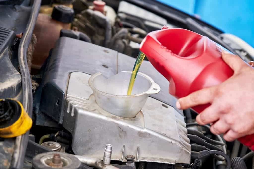Hands of a mechanic repairman adding or pouring oil to the car engine