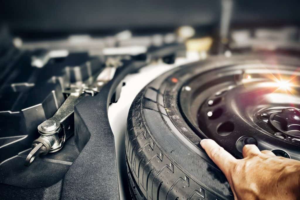 Mechanic hand taking spare tire in the trunk of the vehicle, Does The Lexus NX Have A Spare Tire?