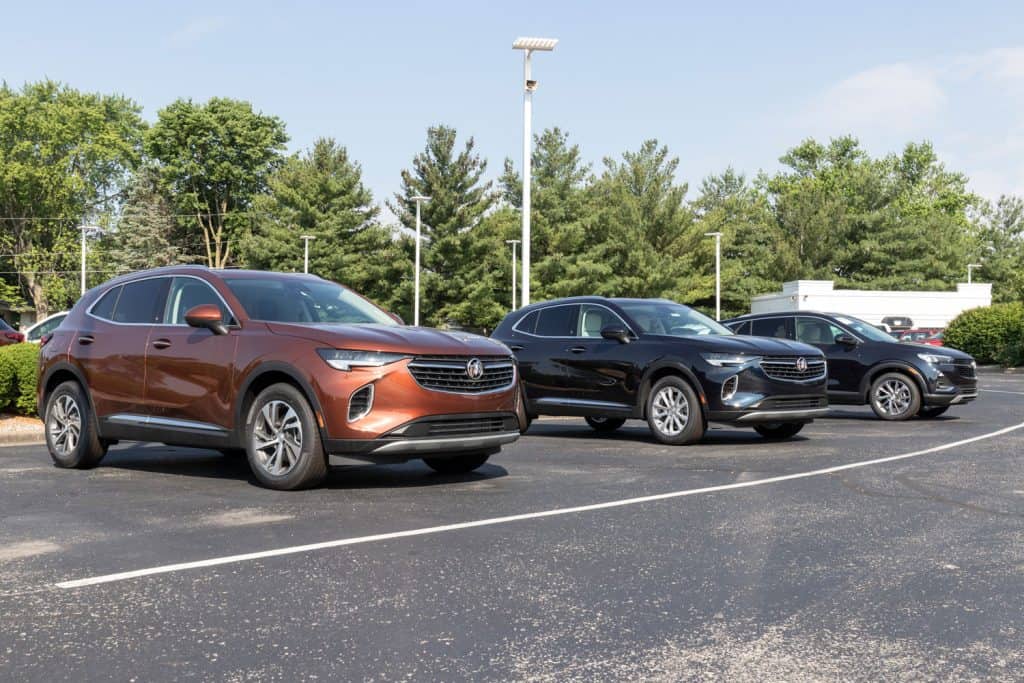 Three different trims of Buick Envision SUVs at a dealership