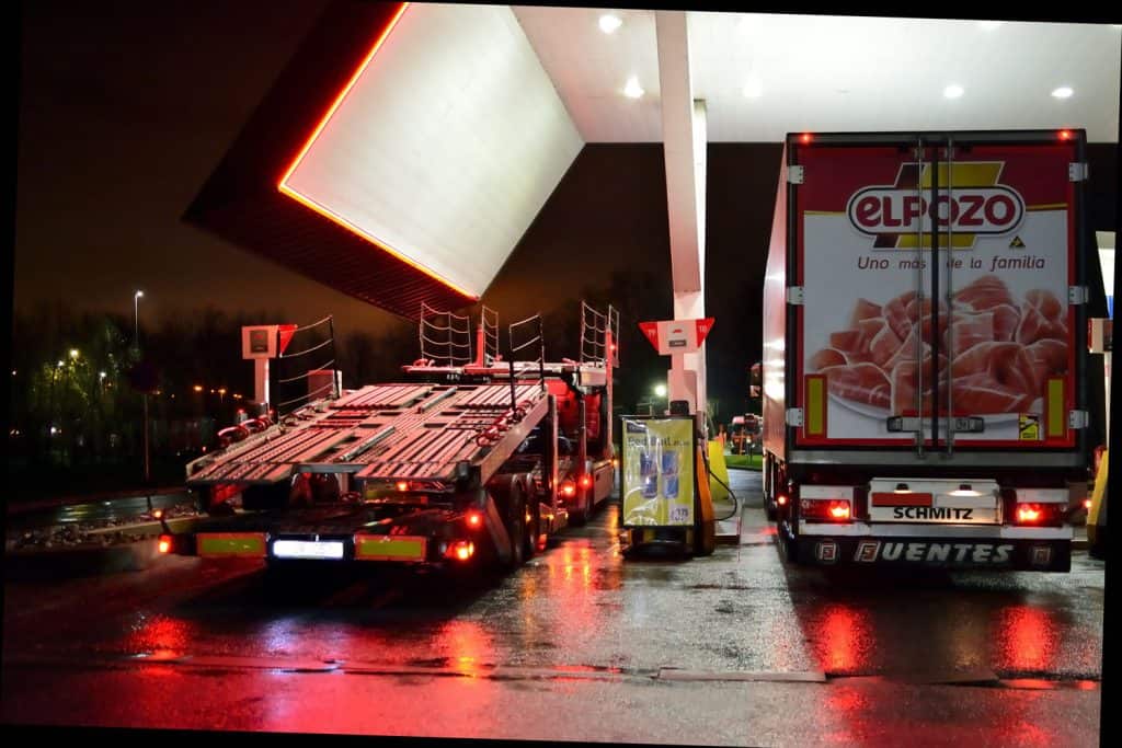 Two huge cargo trucks filling up gas at a gasoline station
