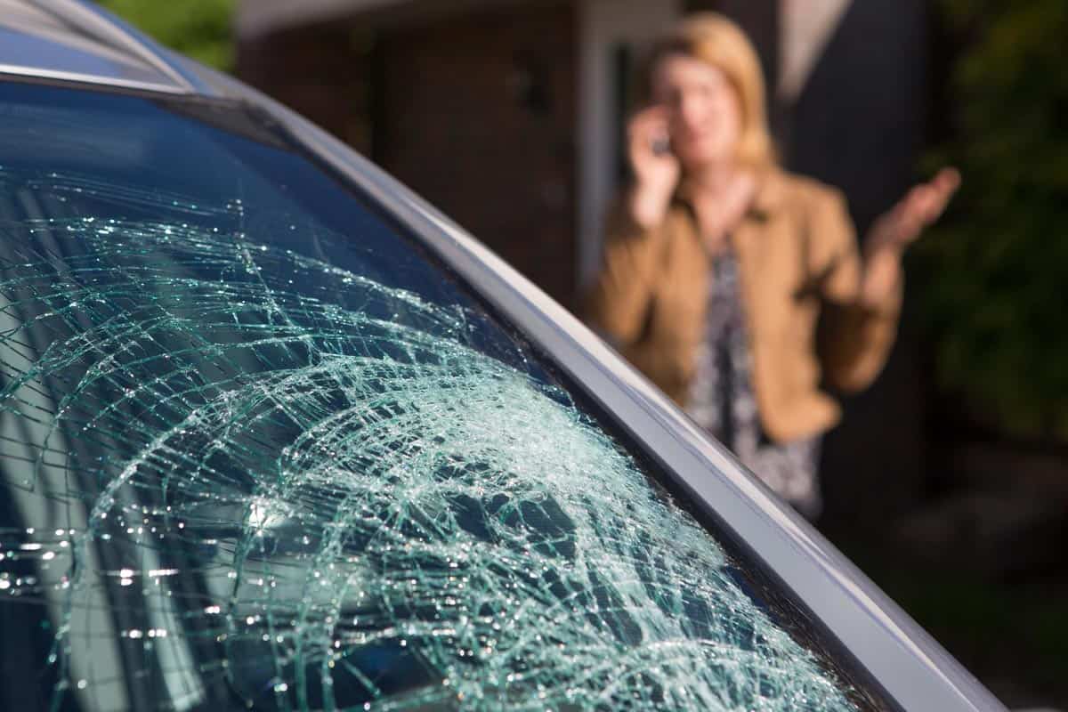 Woman phoning for help after car windshield has broken, Do Car Warranties Cover Windshields?
