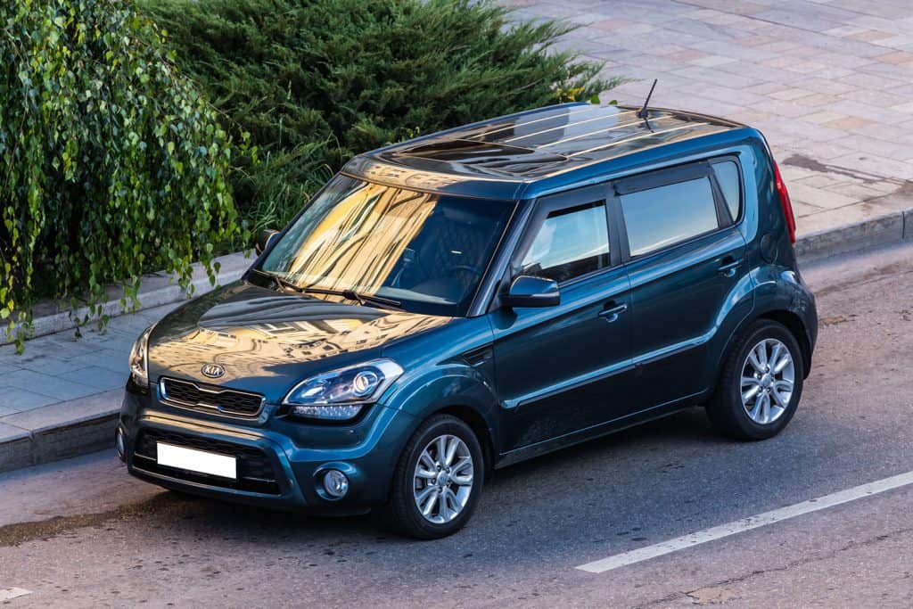 blue Kia Soul is parked on the street on a warm autumn day against the backdrop of a street