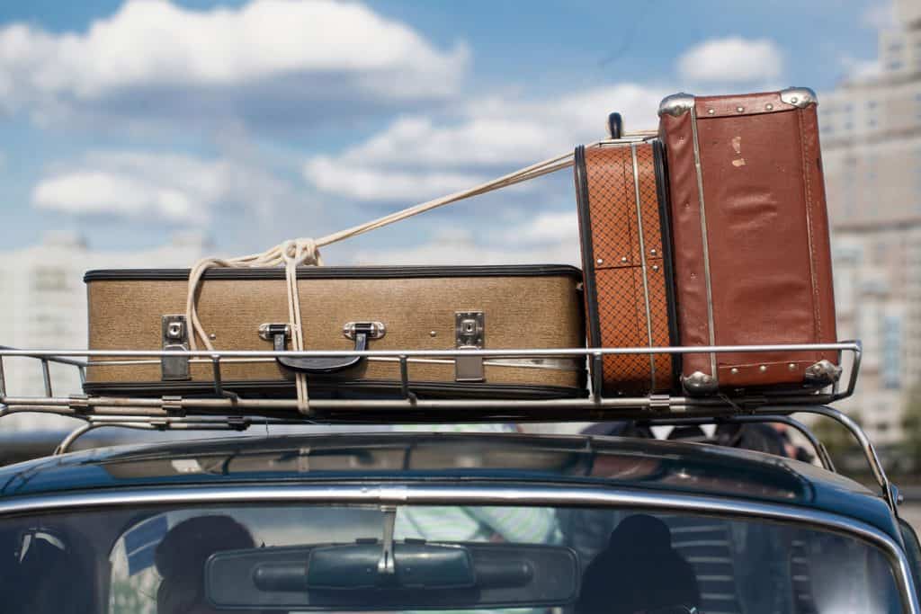 suitcases tied with rope on a car roof