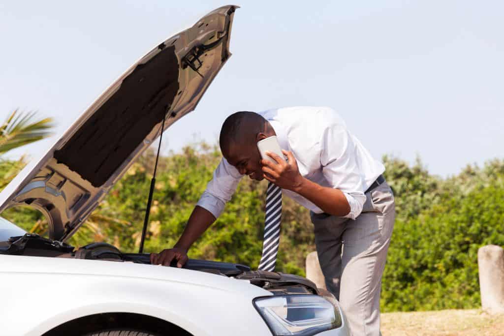 young man with broken down car with bonnet open calling for help