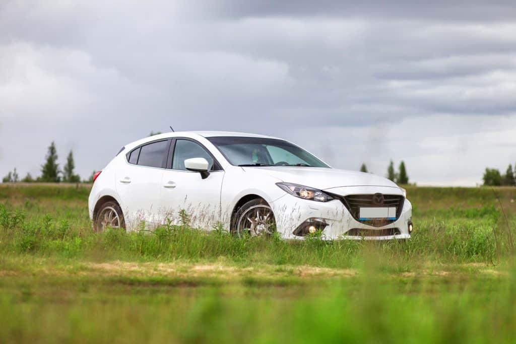 A beautiful white colored Mazda 3 at a field