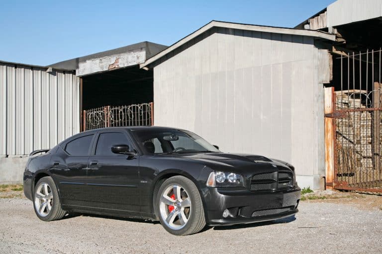 A black Dodge Charger SRT-8 model sports car in front of an industrial building, Does Dodge Charger Need Premium Gas Or Regular?