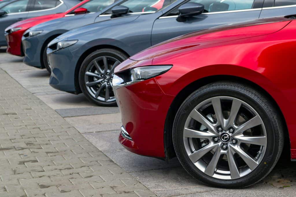 A line up of different colored Mazda 3s at a dealership