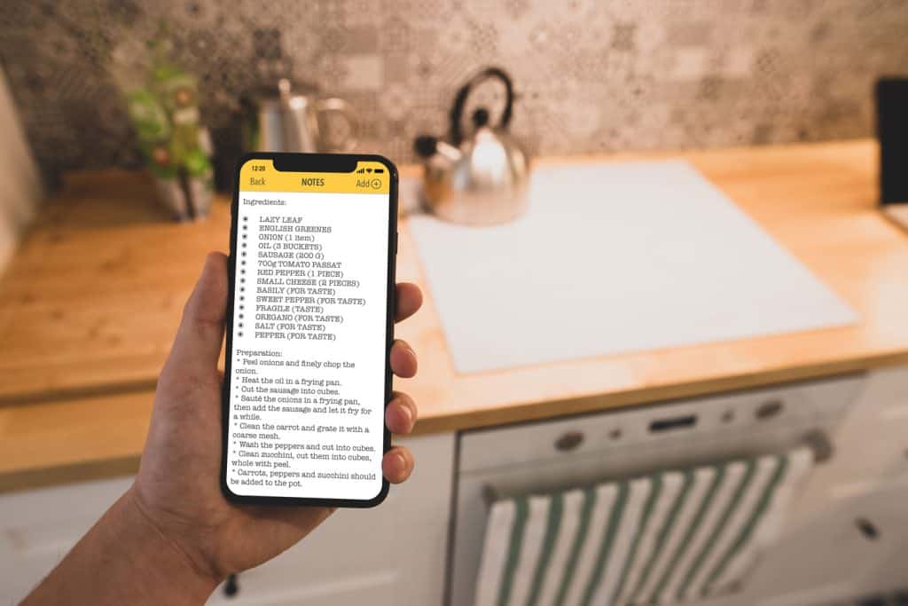 A man reads recipe on a smartphone against of kitchen background