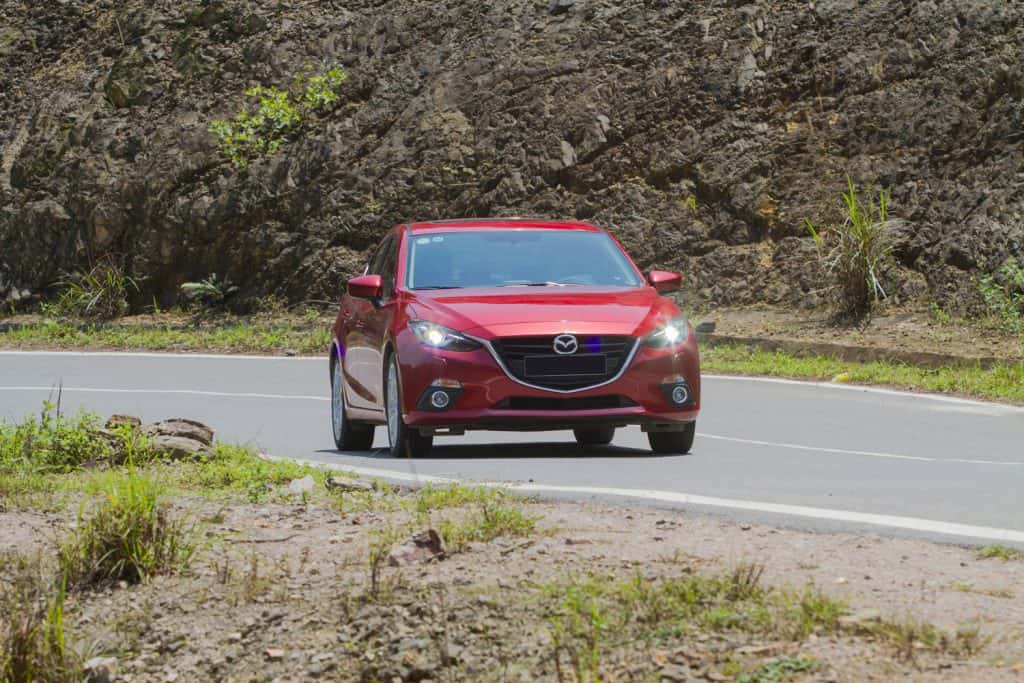 A red colored Mazda 3 moving on the road