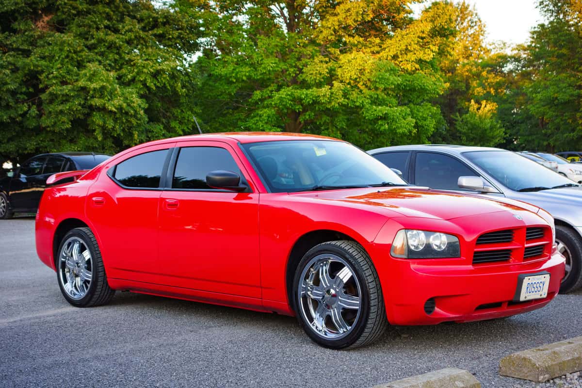 A red colored, first generation Dodge Charger LX parked in a parking lot