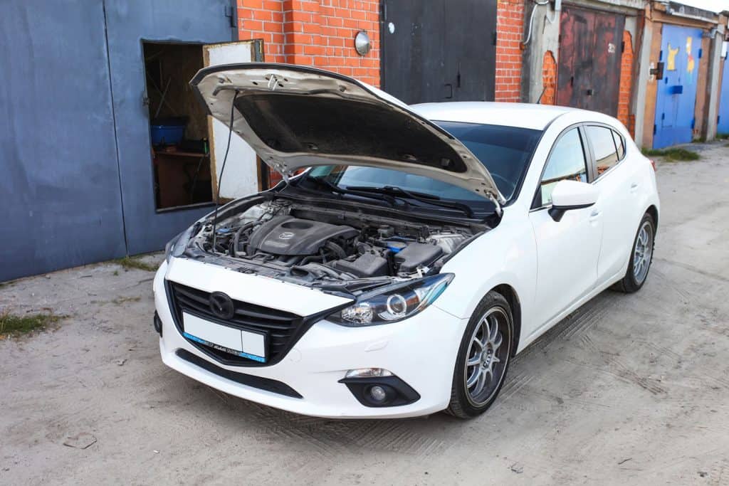 A white Mazda 3 with an opened hood