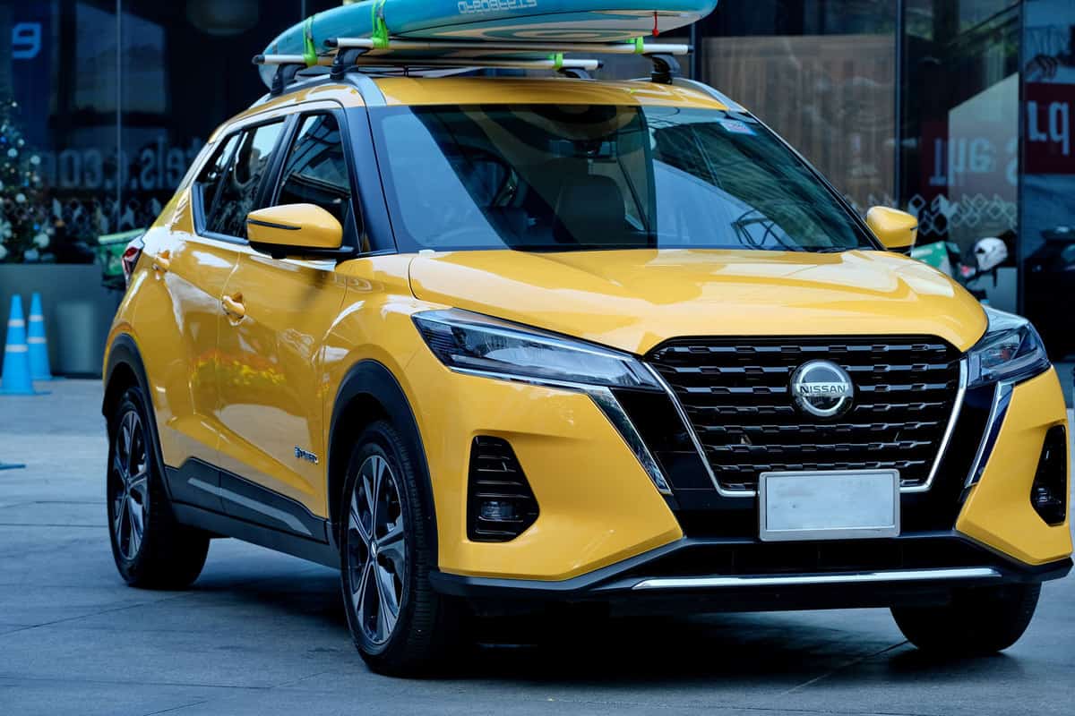 A yellow Nissan Kicks packing a surfboard on top