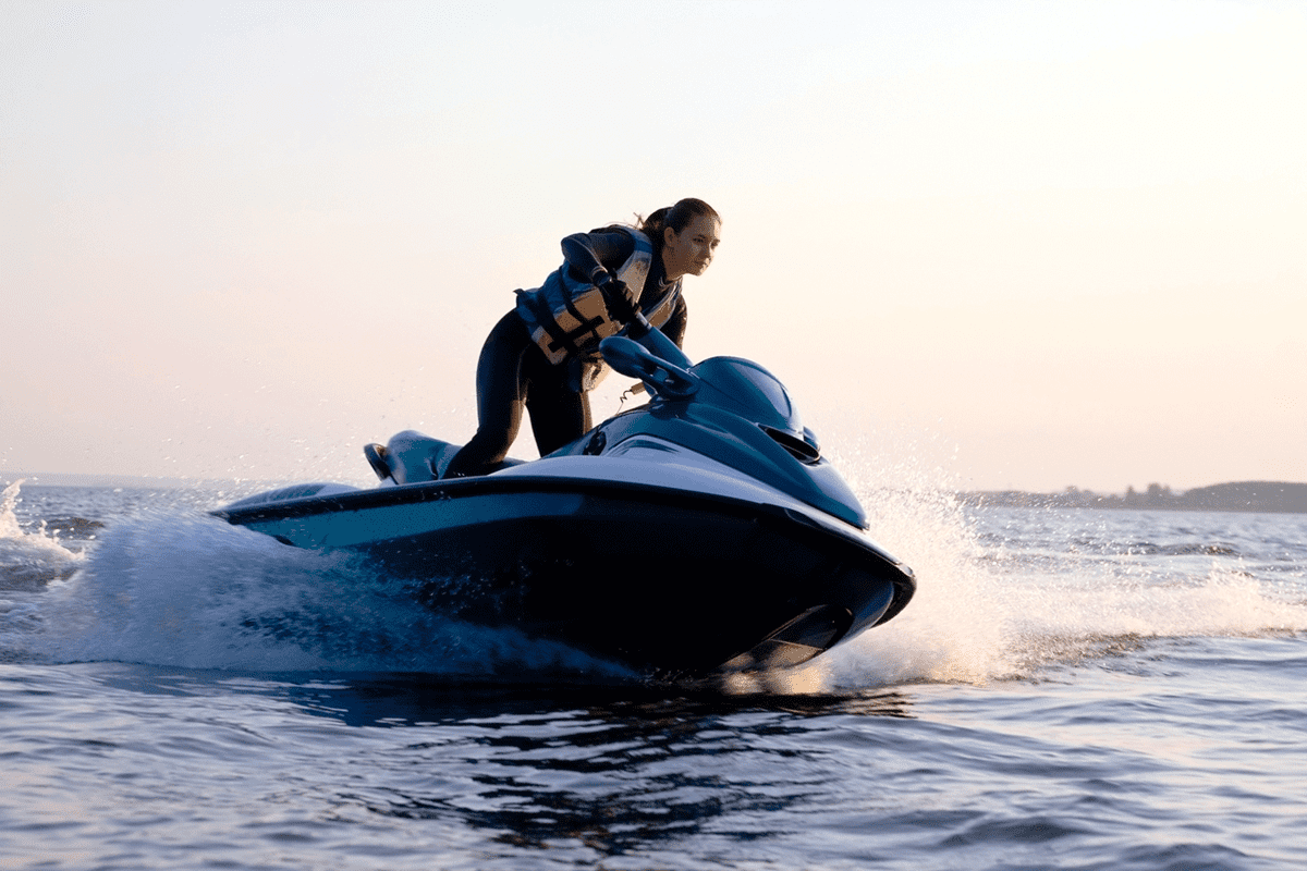 Beautiful girl riding her jet skis in the sea at sunset