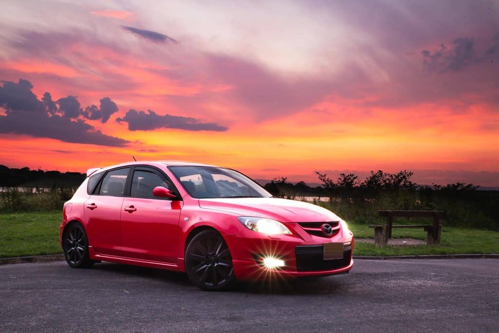Beautiful red Mazda 3 sport shot in a carpark by the river during a gorgeous scenic colourful sunrise