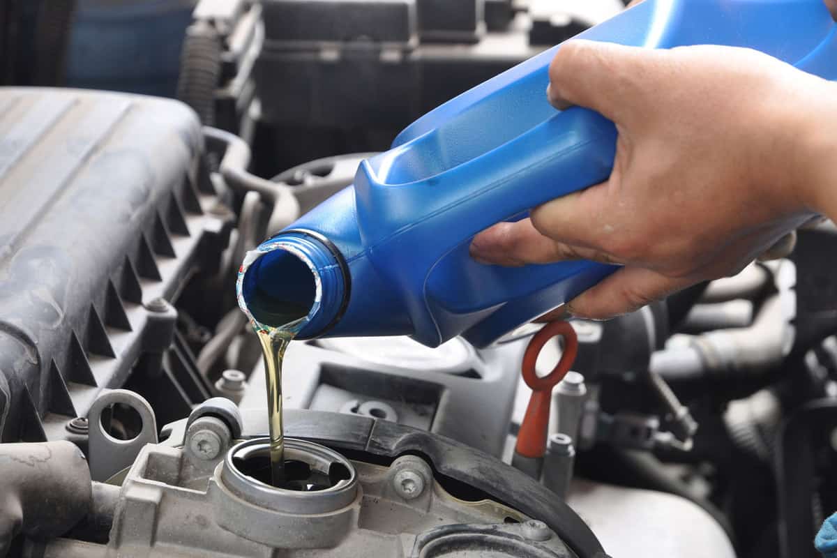 Car mechanic pouring new motor oil on the engine