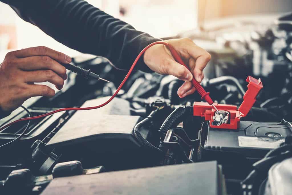Car mechanic working in auto repair service and maintenance of car battery
