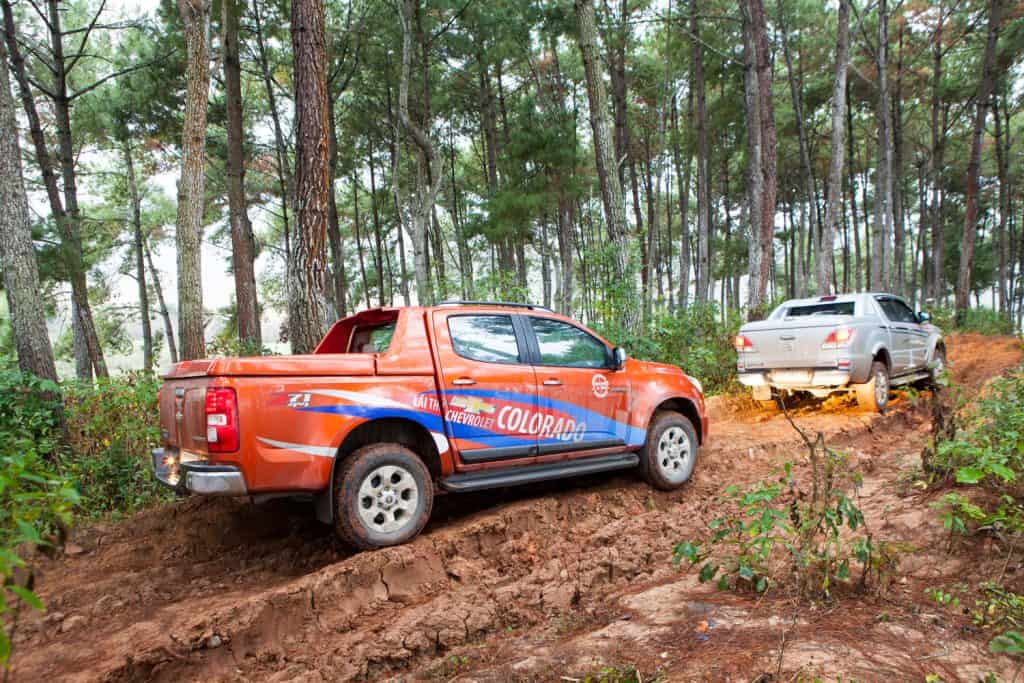 Chevrolet Colorado and Mazda BT-50 pick-up cars running on mud road