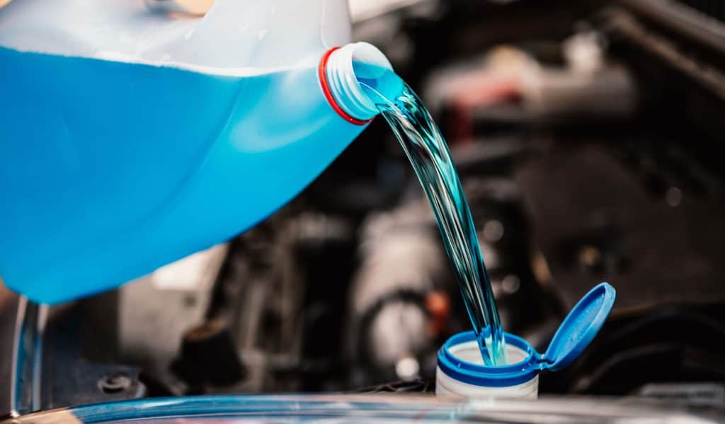 Filling a windshield washer tank with an antifreeze in winter cold weather.