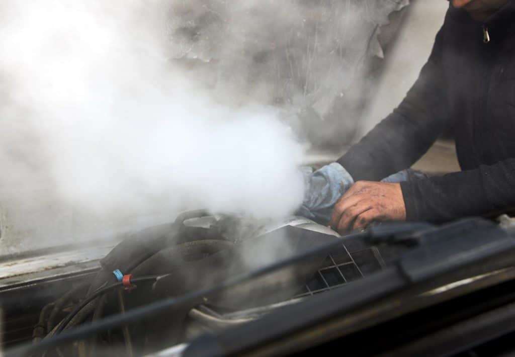 Man mechanic repair a smoking engine of his overheated car