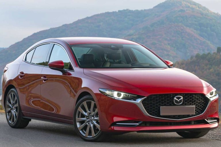 A Mazda3 Sedan on the road with a beautiful mountain on the back, Does Mazda 3 Have AWD? [By Year And Trim Level]