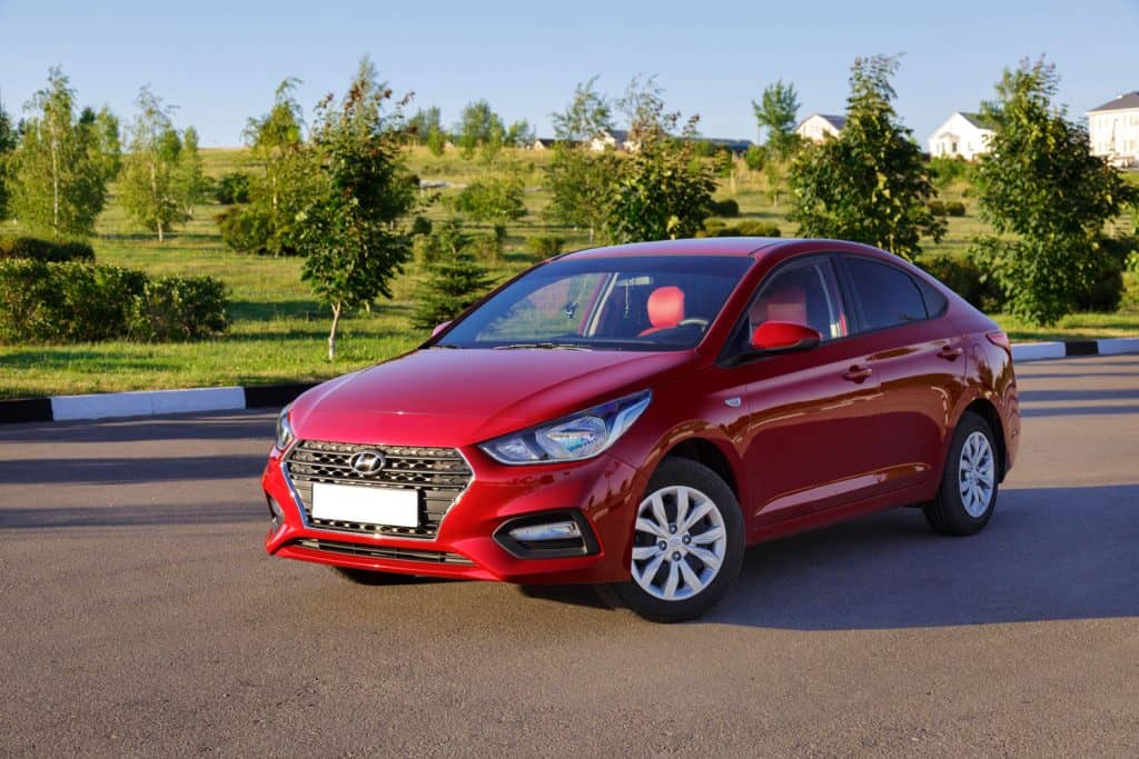 Red Hyundai Solaris parked on a summer sunny day.