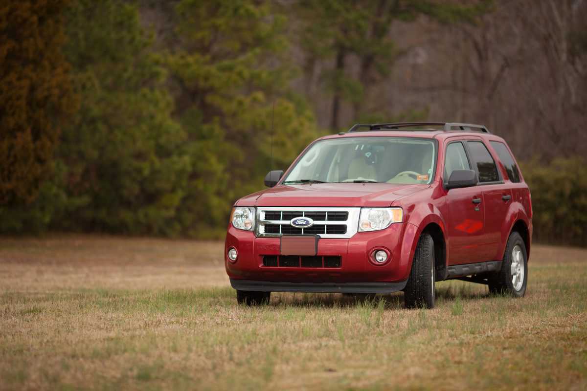 Red ford escape sports utility vehicle parked on an empty field