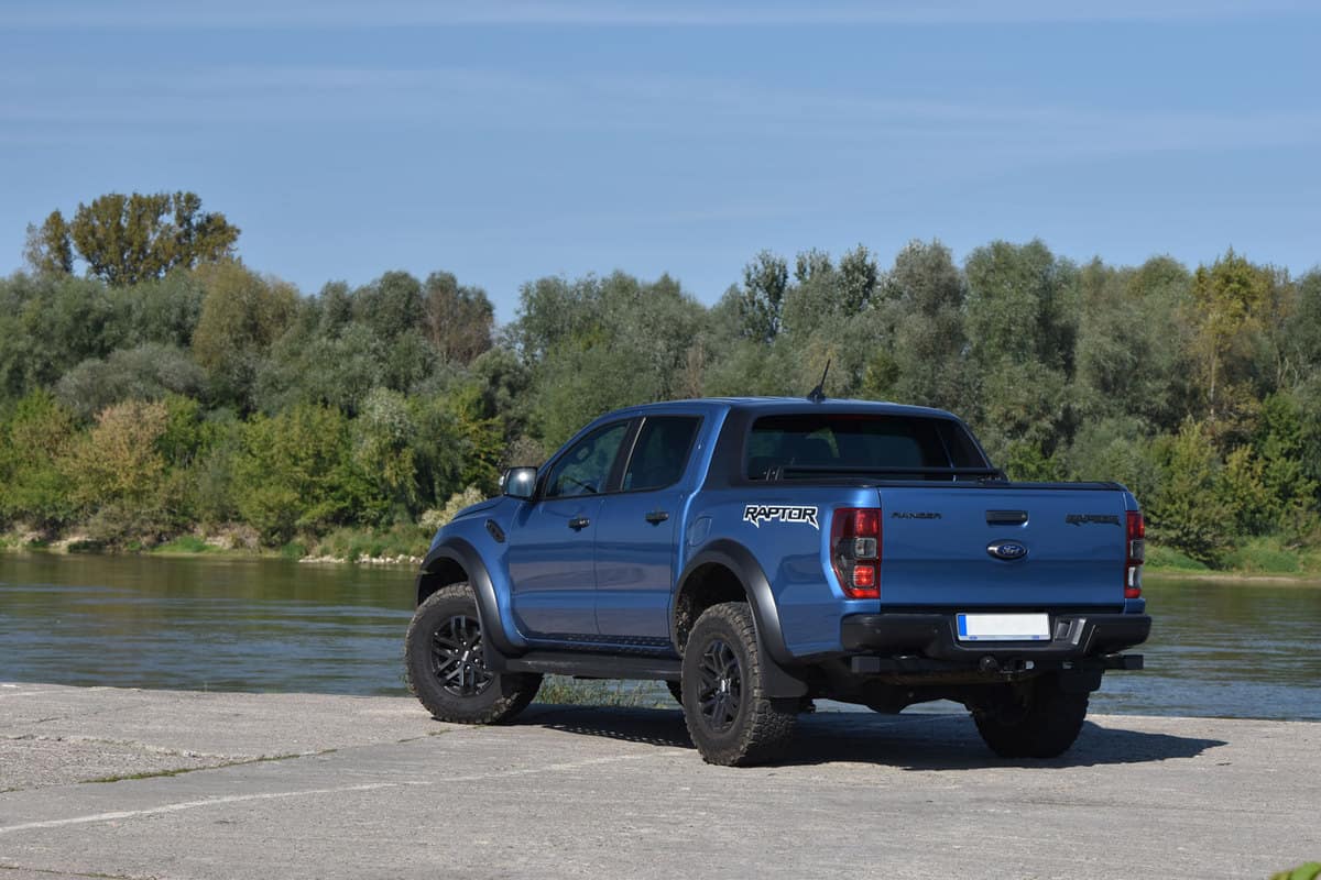 A blue Ford Ranger Raptor parked near a body of water