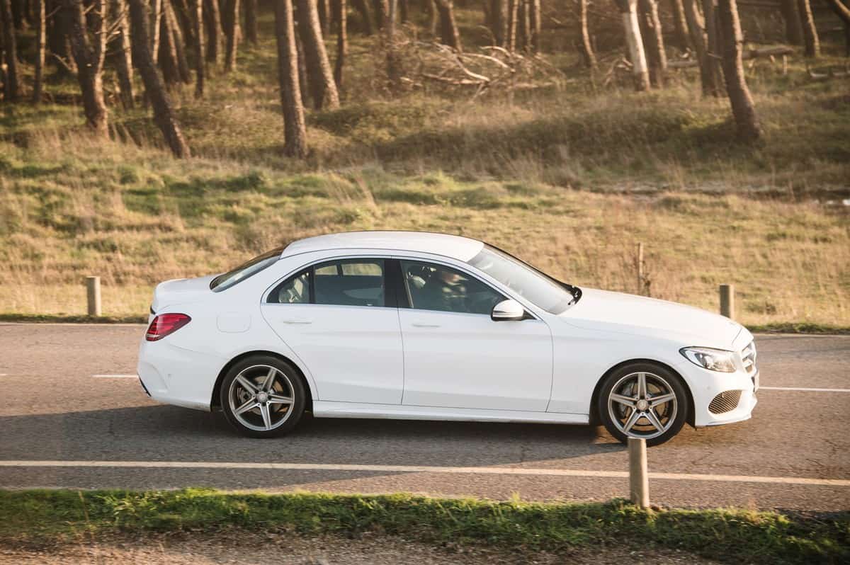 A side view of a white Mercedes-Benz C Class on a road