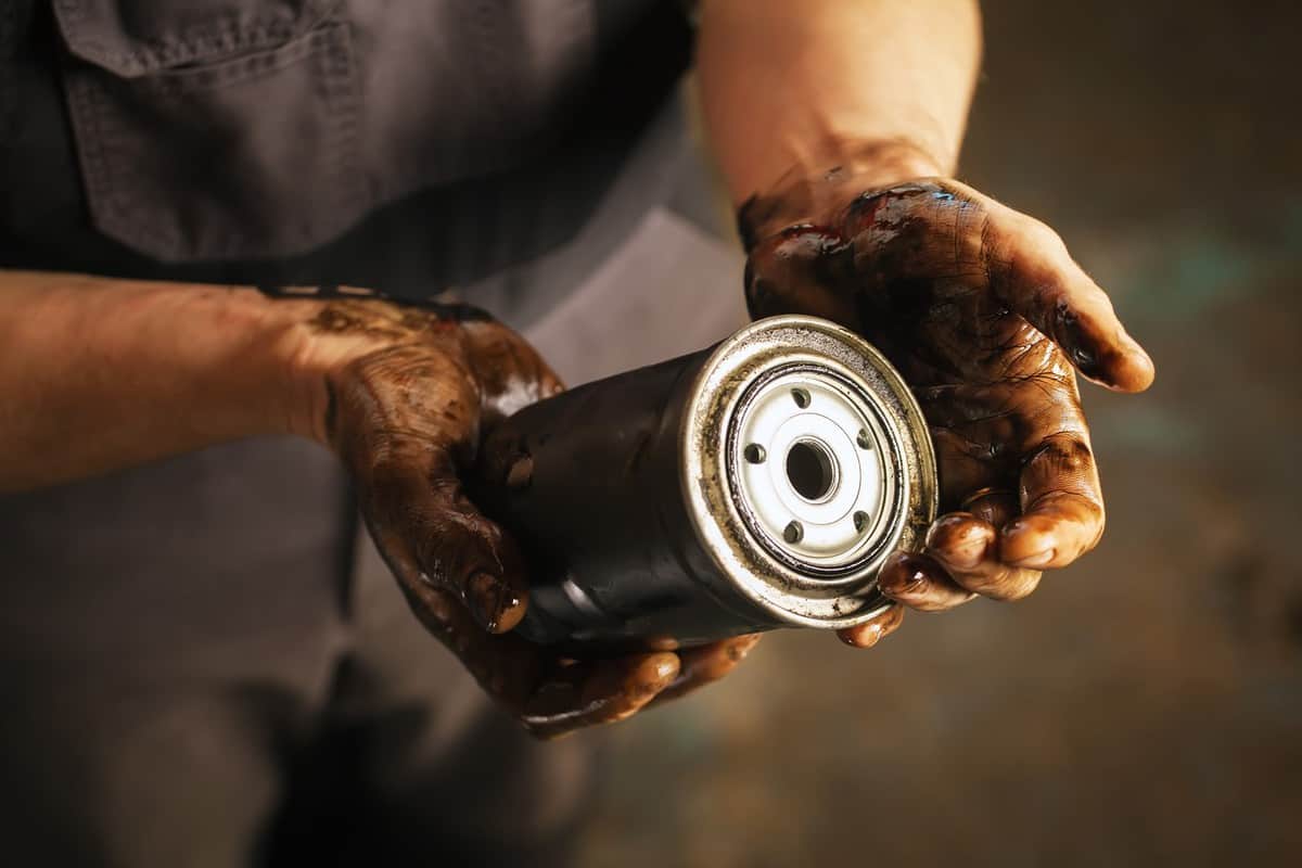 Auto mechanic with dirty hands and oil filter. Service maintenance.