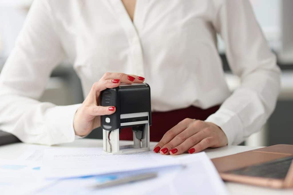 Businesswoman puts stamp on credit documents at work desk