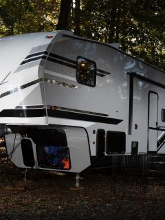 A camping trailer at a forested area just before sundown, Toy Hauler Dimensions: How Wide And Tall Are Toy Haulers