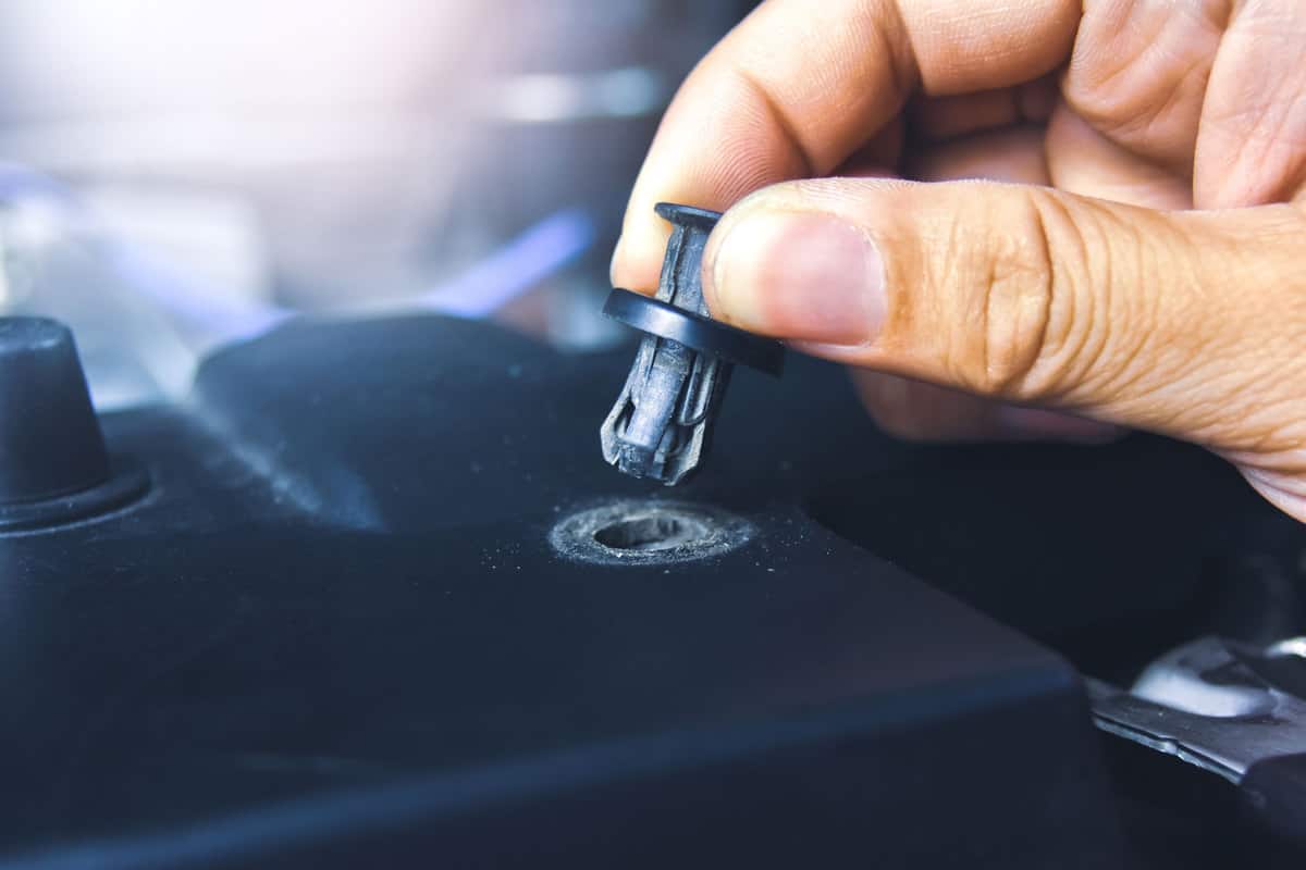 Car mechanic removing plastic rivets in the car engine