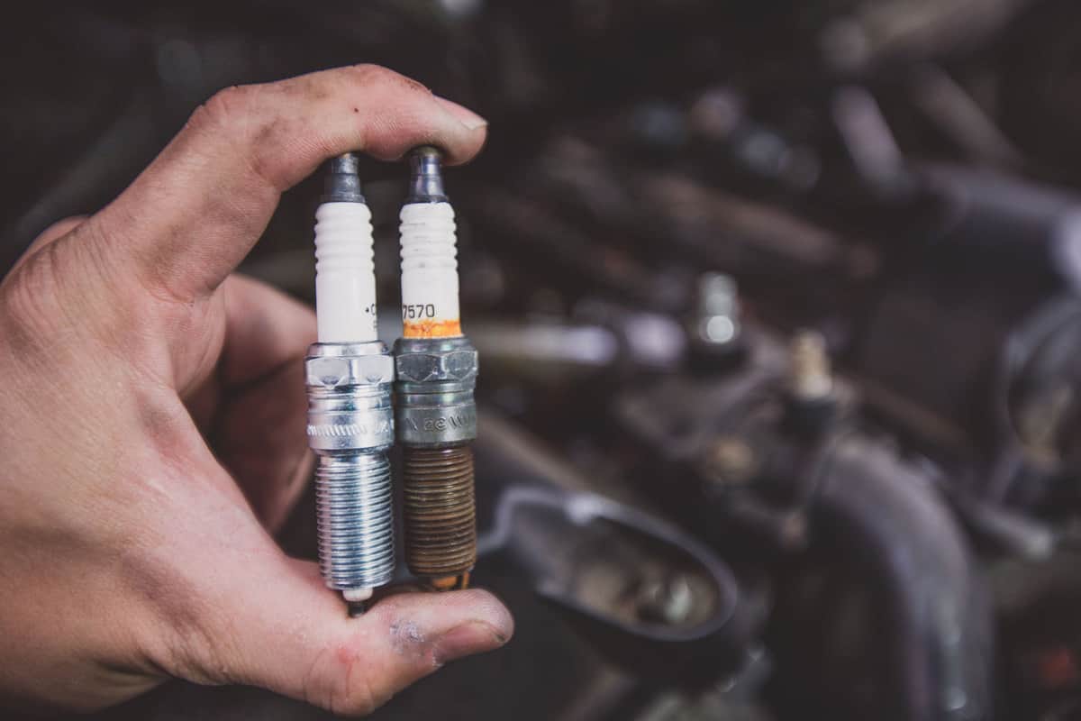 Car mechanic replacing the old spark plug with a new one
