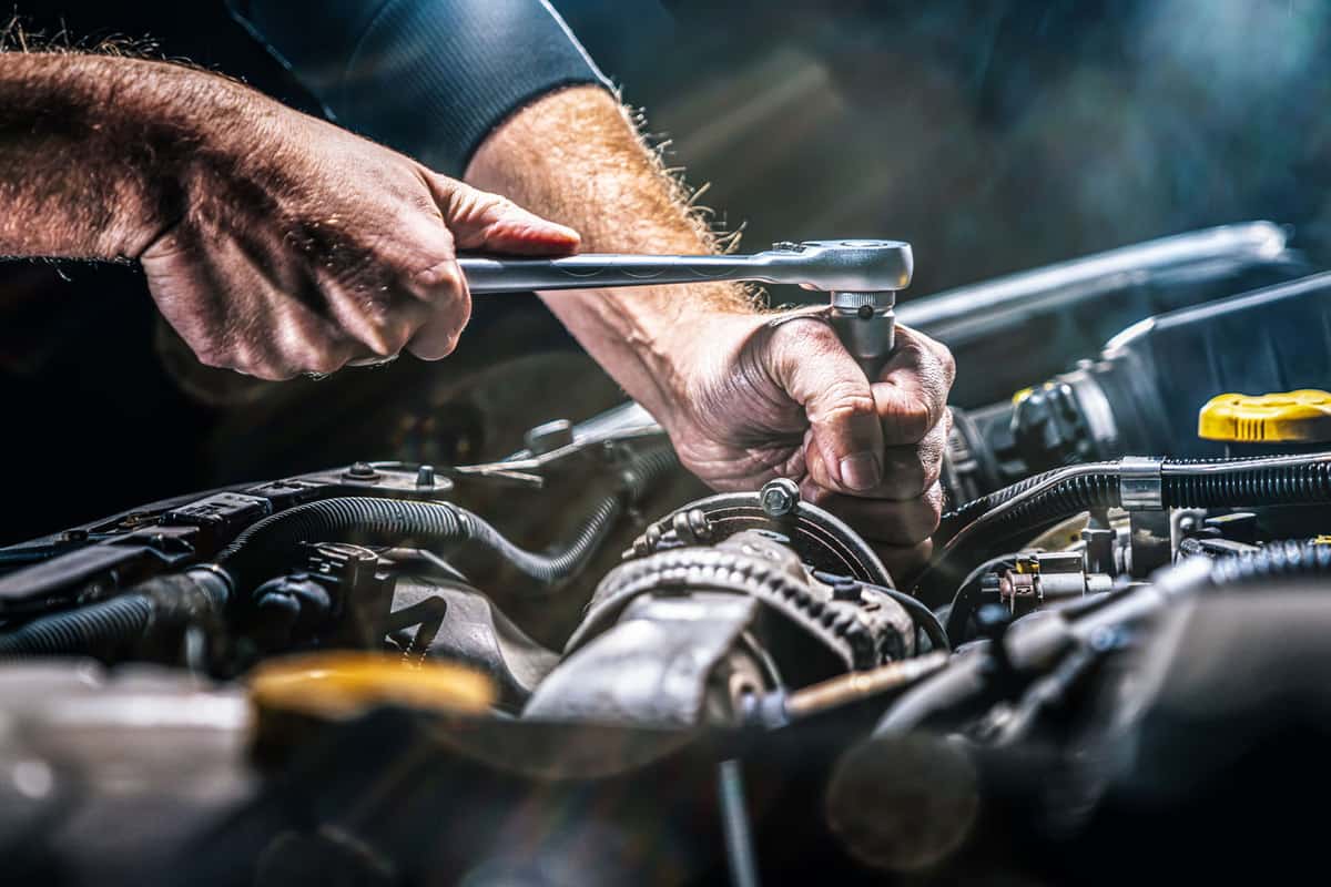 Car mechanic using a socket wrench to check the battery