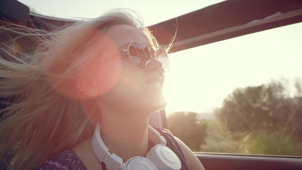 Happy woman travelling in a car with sunroof