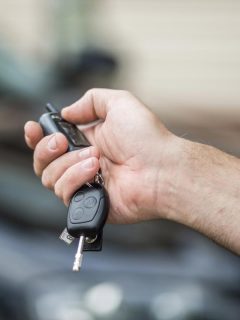 A man pressing the car key fob button to start the car, How To Use Remote Start On GMC Acadia