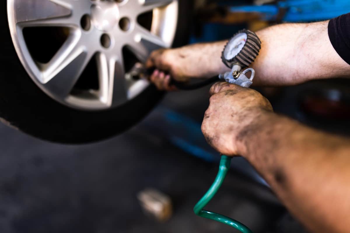 Man's hand checking tyre pressure.