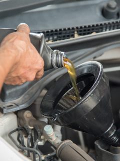Mechanic draining engine oil from a car for an oil change at an auto shop - How Long To Let Oil Drain