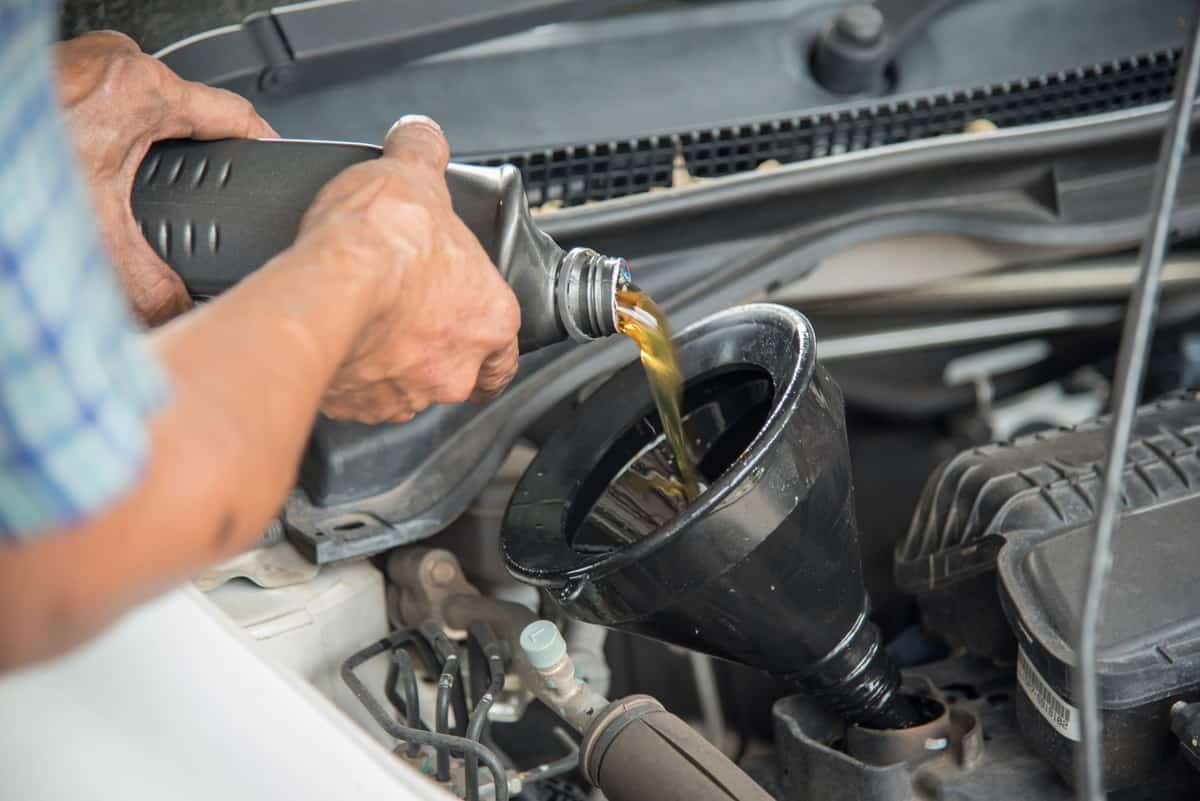 Mechanic draining engine oil from a car for an oil change at an auto shop