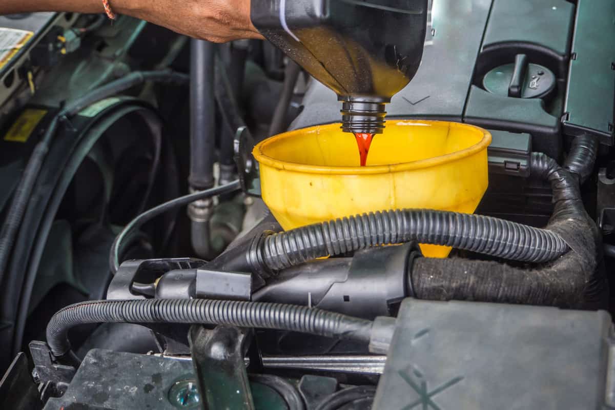Mechanic pouring a container full of transmission fluid