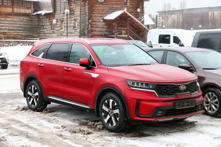 Red crossover Kia Sorento in the city street - How Much Can A Kia Sorento Tow? [Can It Tow A Camper?]