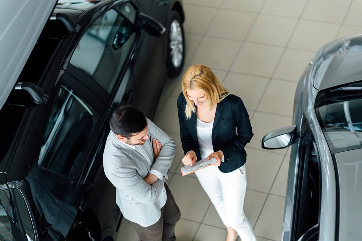 Salesperson showing vehicle to potential customer in dealership