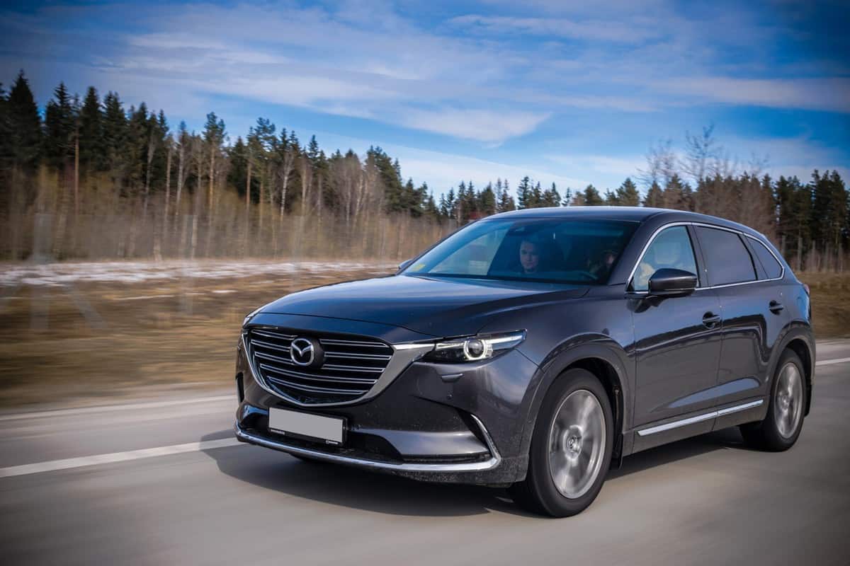 Second generation of Mazda CX-9 drives on a highway during the test-drive event. Mazda CX-9 is a truly striking 7-passenger SUV.