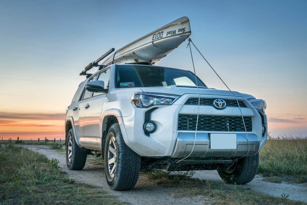 Toyota 4Runner SUV (2016 Trail edition) with a canoe (Sea Wind by Kruger Canoes) on roof racks driving during summer vacations on Kansas back country roads