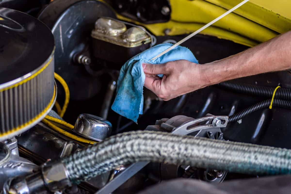 Technician using a dipstick to measure the transmission fluid